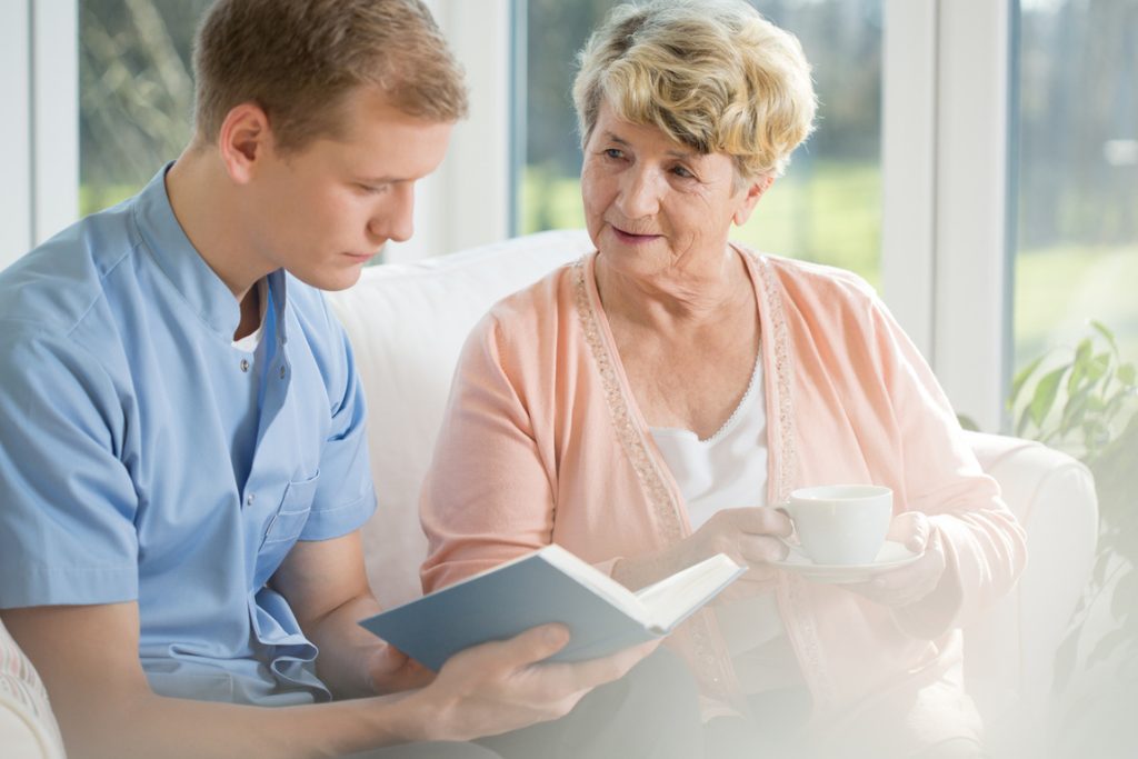 older woman talking with younger man reading a book
