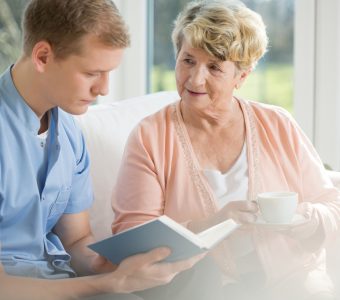 older woman talking with younger man reading a book