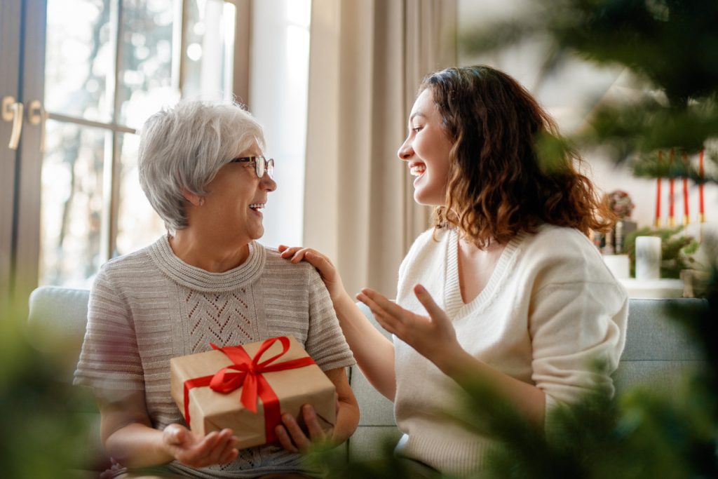 Senior mom and her adult daughter exchanging gifts.