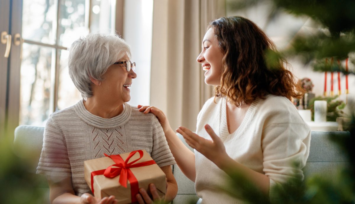 Senior mom and her adult daughter exchanging gifts.