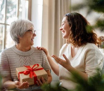Senior mom and her adult daughter exchanging gifts.