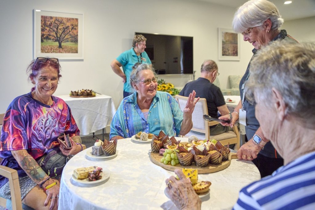 a group photo of aged care residents being served food by an aged care worker