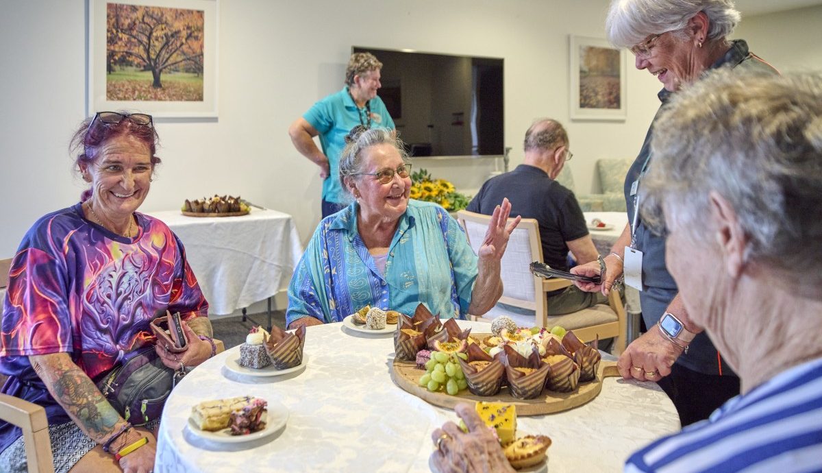a group photo of aged care residents being served food by an aged care worker