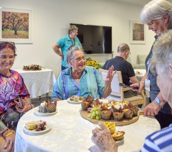 a group photo of aged care residents being served food by an aged care worker